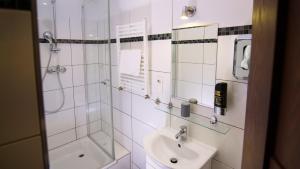 a white bathroom with a sink and a shower at Hirsch Hotel Hanau in Hanau am Main