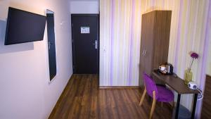 a hotel room with a desk and a purple chair at Hirsch Hotel Hanau in Hanau am Main