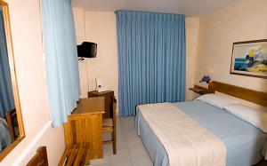 um quarto com uma cama, uma mesa e uma televisão em Hotel Marinella em Pizzo