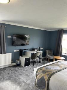 a bedroom with a bed and a desk and a tv at Dolphin Hotel Cambridge in St Ives
