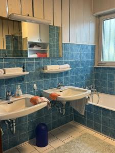 uma casa de banho em azulejos azuis com 2 lavatórios e uma banheira em Haus mit Pool und Panoramablick em Hirschaid