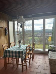 uma sala de jantar com mesa, cadeiras e janelas em Haus mit Pool und Panoramablick em Hirschaid