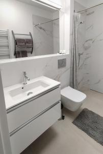 a white bathroom with a sink and a toilet at Piaskowa 13 - Apartamenty dla Podróżujących bez Dzieci in Mikoszewo