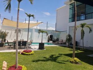 a yard with palm trees and a swimming pool at Bella Casa Blanca in El Castillo