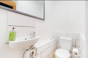 La salle de bains blanche est pourvue d'un lavabo et de toilettes. dans l'établissement Newly renovated 4BR in Kings Cross with Garden, à Londres
