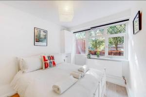 a white bedroom with a bed and a window at Newly renovated 4BR in Kings Cross with Garden in London