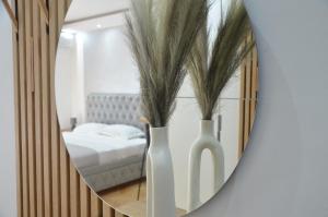 twee witte vazen met planten voor een spiegel bij Apartman La Luna, Vrnjacka Banja in Vrnjačka Banja