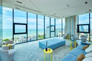 a living room with a blue couch and large windows at Best Pool with 360 View of Pattaya & Best Location in Pattaya Central