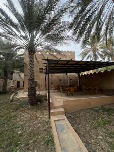 a patio with a palm tree and a table and chairs at Mall Aldakhil House in Al Ḩamrāʼ