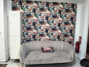 1 sofá en la sala de estar con papel pintado con motivos florales en La MARINA en Alicante