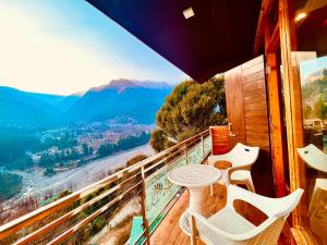 a balcony with a table and chairs and a view at Rockland Cottage, Manali - Centrally Heated & Air Cooled Premium Rooms in Manāli