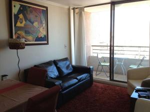 sala de estar con sofá de cuero negro y balcón en Miramar, en Viña del Mar