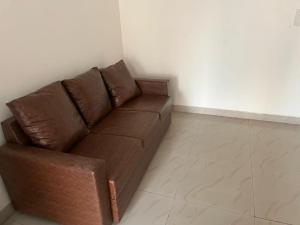 a brown couch in a room with a white wall at 2BHKapartment-Calm and natural in Faridabad