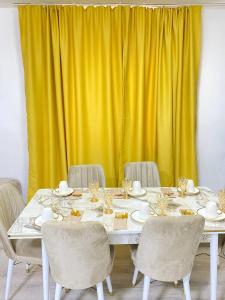 a white table with chairs and a yellow curtain at Супер квартира для большой семьи in Almaty