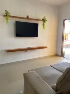 sala de estar con TV de pantalla plana en la pared en Casa Akua, en São Miguel dos Milagres