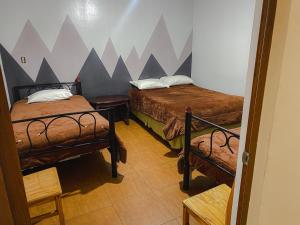 a room with two beds and a wall with mountains at Latacunga Hostel in Latacunga