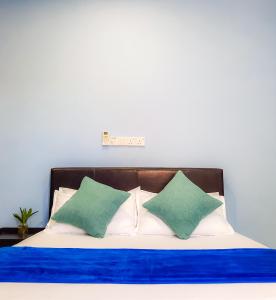 a bed with blue and white sheets and green pillows at Hide Inn Blue in Nilandhoo