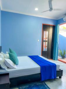 Cama en habitación con pared azul en Hide Inn Blue, en Nilandhoo
