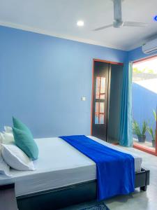 a bedroom with blue walls and a bed with pillows at Hide Inn Blue in Nilandhoo +70 photos