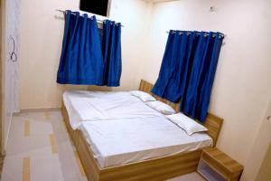 a small bed with blue curtains in a room at Hotel Bhagwaan Das In Varanasi in Varanasi