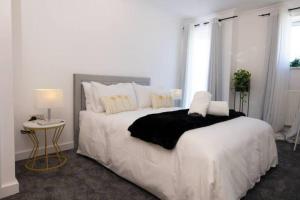 a white bedroom with a large bed and a table at No15 Fivedom - Charming & Cosy Apartment in Southampton
