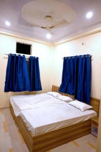 a bedroom with a bed with blue curtains at Hotel Bhagwaan Das In Varanasi in Varanasi