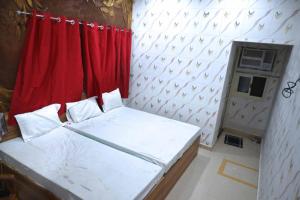 a small room with a bed and a red curtain at Hotel Bhagwaan Das In Varanasi in Varanasi