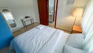 a bedroom with a white bed and a mirror at Salamandra Guest House in Nahariyya