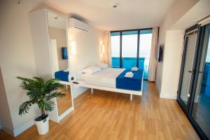 1 dormitorio con cama, espejo y planta en Panorama Batumi Beach Resort en Batumi