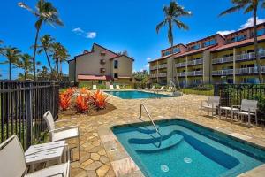 a swimming pool with chairs and a building at 1BR Condo at Oceanfront Resort Kapaa Shore in Kapaa