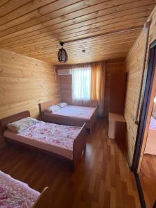 um quarto com 2 camas num chalé de madeira em Дом Отдыха Айзада em Qabanbay