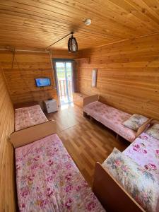 um quarto com 4 camas num chalé de madeira em Дом Отдыха Айзада em Qabanbay