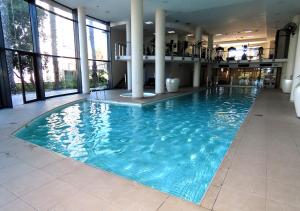 a large swimming pool in a building with large windows at Cape Town Luxury Stays Knightsbridge Luxury Apartment Century City in Cape Town