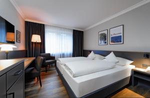 ブレーメンにあるATLANTIC Hotel Landgut Hornのベッドとデスクが備わるホテルルームです。