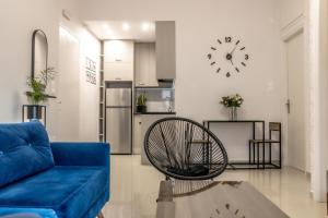 a living room with a blue couch and a clock on the wall at Elichrysos Cozy Apartment in Heraklion