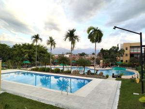una gran piscina con palmeras y un edificio en Apartamento armenia, en La Tebaida