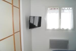 a tv on a wall next to a window at Chambre d'hôte dans une propriété avec piscine 