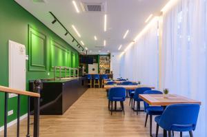 蒙蒂茹的住宿－2M BOUTIQUE HOTEL，餐厅拥有绿色的墙壁和桌子以及蓝色的椅子