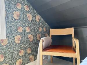 uma cadeira num quarto com papel de parede floral em Bed and Brunsj, Sand em Sand
