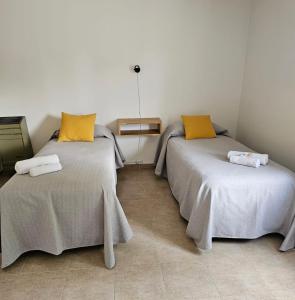 エル・カラファテにあるAlameda Apartの黄色い枕が付いた部屋のベッド2台