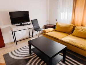 a living room with a yellow couch and a tv at Salamandra Guest House in Nahariyya