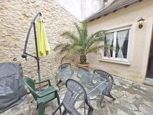 eine Terrasse mit einem Tisch, Stühlen und einem Sonnenschirm in der Unterkunft Triplex Sisley - Maison Atypique avec Cour Extérieure in Moret-sur-Loing