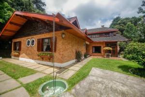 a house with a fountain in the yard at Suítes para locação próximo ao Capivari in Campos do Jordão