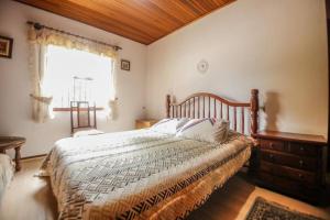 a bedroom with a bed with a wooden headboard and a window at Suítes para locação próximo ao Capivari in Campos do Jordão