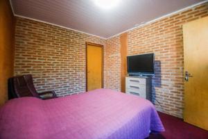 um quarto com uma cama rosa e uma televisão de ecrã plano em Suítes para locação próximo ao Capivari em Campos de Jordão