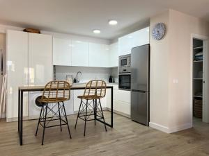 サアラ・デ・ロス・アトゥネスにあるAPARTAMENTO ATLANTERRA PLAYA PRIMERA LINEAのキッチン(バースツール2つ、冷蔵庫付)