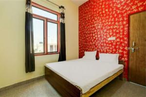a bedroom with a bed with a red wall at GRG Hotel M J Agra in Agra