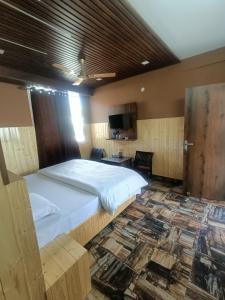 - une chambre avec un grand lit et une télévision dans l'établissement Ramandeep Stays, à Dharamshala
