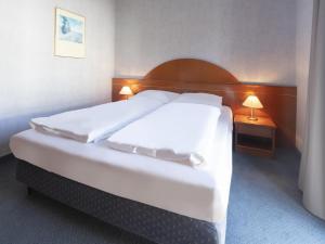 sypialnia z dużym białym łóżkiem z dwoma stołami w obiekcie B&B HOTEL Gotha-Hbf w mieście Gotha