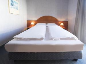 two beds in a hotel room with white pillows at B&B HOTEL Gotha-Hbf in Gotha